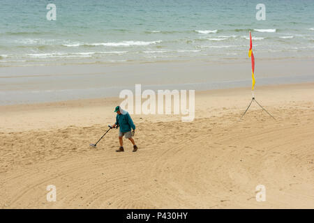 Homme avec un détecteur de métal de la numérisation d'un plage pour les trésors cachés ou jeté des pièces. Banque D'Images