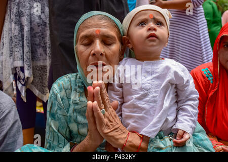 Ganderbal, Inde. 20 Juin, 2018. Dévot hindou avec un enfant est considéré en accomplissant des rituels (puja) pendant le festival. bhavanis kheer kheer bhavan festival est marqué dans Kheer Bhavani Temple dans Tulmulla Ganderbal quelques 21 kms de Srinagar, capitale d'été du Jammu-et-Cachemire. OM est le mantra sacré dans l'hindouisme. Il apparaît à la mendicité et la fin de la plupart des récitations sanscrites. Credit : SOPA/Alamy Images Limited Live News Banque D'Images