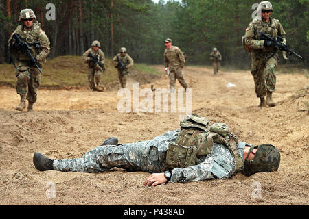 Soldats affectés à la Batterie B, l'Escadron d'artillerie, 2e régiment de cavalerie se précipitent vers une victime simulée joué par un soldat polonais pendant le combat gareautrain Cours de certification, 8 juin, à Adazi Base militaire, la Lettonie. Lutter contre les médecins la supervision de l'évaluation a produit l'expérience aussi réaliste que possible à l'aide de la fumée et des grenades simulée.(U.S. Photo de l'armée par le Sgt. Paige Behringer, 10e Appuyez sur Camp de siège) Banque D'Images