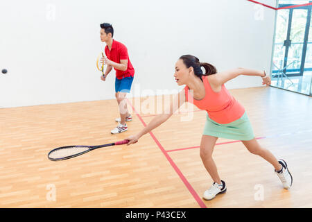 Femme chinoise concurrentiel tenant la raquette lors d'un jeu de squash Banque D'Images