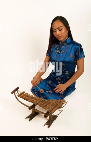 Femme chinoise jouant un xylophone de bambou avec un hérisson en bois. Instrument traditionnel. Banque D'Images