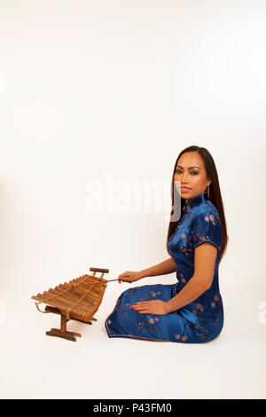 Femme chinoise jouant un xylophone de bambou avec un hérisson en bois. Instrument traditionnel. Banque D'Images