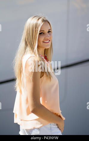 Belle fille blonde debout sur un quai commercial et smiling at the camera Banque D'Images