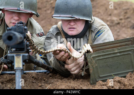 Le 1er juin 2016, des reconstituteurs vêtus d'uniformes de l'époque du jour J ont participé à une reconstitution historique à Omaha Beach, en France, devant le musée Overlord. L'événement commémore le 72e anniversaire du débarquement du jour J, représentant les parachutistes et les opérations d'infanterie, soulignant l'histoire de la seconde Guerre mondiale, les tactiques militaires et les rôles des unités aéroportées tout en fournissant une documentation éducative et visuelle des scénarios de combat pour les visiteurs et les historiens. Banque D'Images