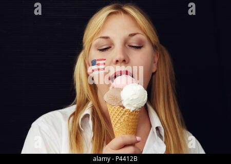 Fille avec le drapeau américain sur son visage la consommation de crème glacée. US Independence Day. Banque D'Images