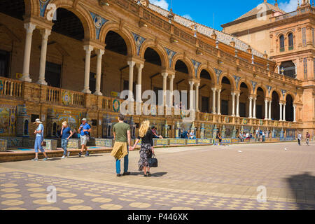 Voyage en Espagne, vue d'un jeune couple de touristes marchant devant une grande colonnade sur la Plaza de Espana un après-midi d'été, Séville, Andalousie, Espagne. Banque D'Images