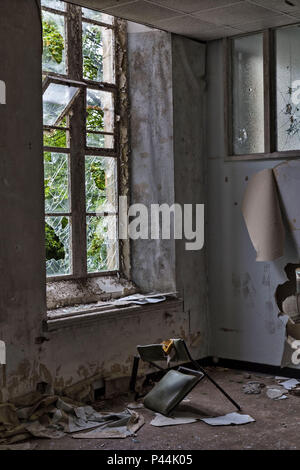 Une chaise brisée à l'intérieur de l'hôpital gallois en décomposition abandonnés Banque D'Images