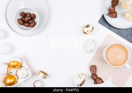 Joyeuses Pâques. Arrière-plan de papeterie élégante avec des œufs en chocolat. or et le blanc des oeufs et des accessoires sur fond blanc. Décoration de table pour les vacances Banque D'Images