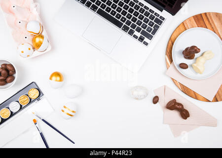 Joyeuses Pâques. Arrière-plan de papeterie élégante avec des œufs en chocolat. L'or et des œufs blancs et des accessoires sur fond blanc. Décoration de table pour les vacances Banque D'Images