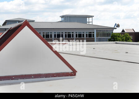 Les travailleurs, en haut à droite, l'exploitation d'un levage de benne, 17 juin 2016, près du toit de l'établissement en construction à l'I.G. Centre de formation et d'éducation de Brown sur McGhee Tyson Air National Guard Base à Louisville, au Tennessee parmi la construction de cette semaine, revêtement gris, les gouttières et descentes sont en cours d'installation. (U.S. Air National Guard photo par le Sgt. Mike R. Smith/libérés) Banque D'Images