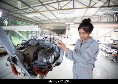 Les hommes asiatiques et les femmes ingénieurs et techniciens sont la réparation d'aéronefs. Banque D'Images