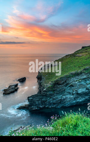 Après une journée nuageuse, le ciel se dégage alors que le soleil se couche sur la pointe de Tintagel en Cornouailles, avec l'ensemble de prévisions pour le soleil et averses en Banque D'Images