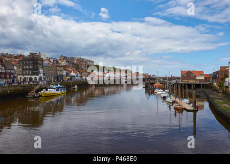 Avis de Whitby Harbour et de la rivière Esk avec bateaux amarrés, les bâtiments bordant la côte et ciel avec quelques nuages, North Yorkshire, England, UK Banque D'Images