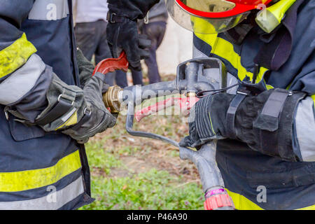 Pompier est d'aider ses collègues à l'Assemblée générale sur le pistolet à eau raccord de flexible. Banque D'Images