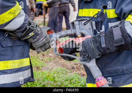 Pompier est d'aider ses collègues à l'Assemblée générale sur le pistolet à eau raccord de flexible. Banque D'Images