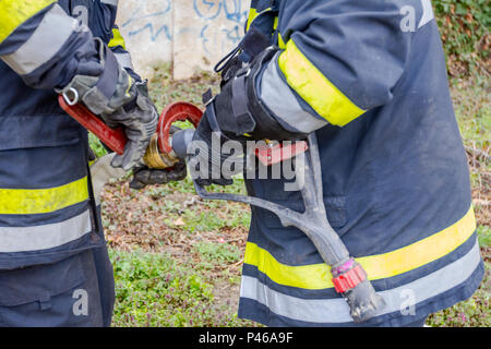 Pompier est d'aider ses collègues à l'Assemblée générale sur le pistolet à eau raccord de flexible. Banque D'Images