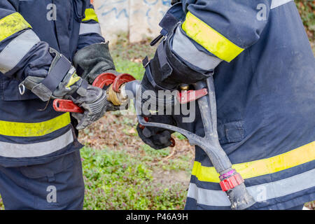 Pompier est d'aider ses collègues à l'Assemblée générale sur le pistolet à eau raccord de flexible. Banque D'Images