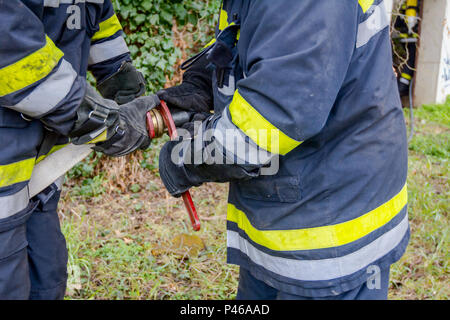 Pompier est d'aider ses collègues à l'Assemblée générale sur le pistolet à eau raccord de flexible. Banque D'Images