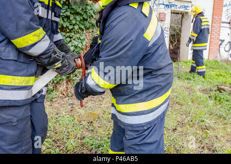 Pompier est d'aider ses collègues à l'Assemblée générale sur le pistolet à eau raccord de flexible. Banque D'Images