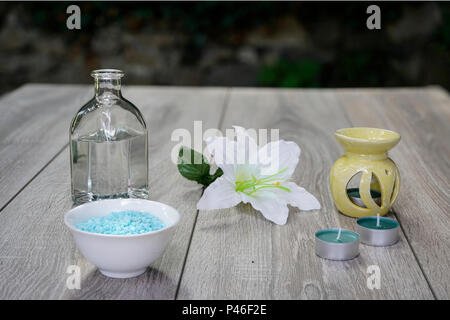 Une bouteille, de fleurs blanches, sels de bain et de bougies, de détente en plein air sur une table en bois... Banque D'Images