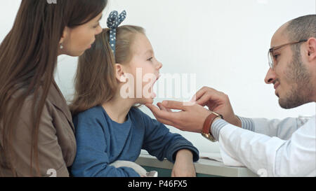 Petite fille ayant l'examen de la gorge avec abaisse-langue par un médecin homme Banque D'Images