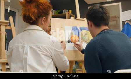 Professeur d'art féminin étudiant expliquant comment faire une demande d'aquarelles Banque D'Images