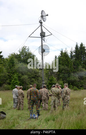 Soldats belges de 6e Groupe CIS (Communication et Systèmes d'information) faire des ajustements à un four micro-ondes de l'armée belge, à la tour de liaison à l'aide d'un four micro-ondes tactique américaine tower installé par les soldats américains de la 39e et 44e Bataillon du signal signal Bataillon expéditionnaire tactique (basé sur Grafenwoehr, Allemagne). Saint Hubert, Belgique, le 28 juin 2016. Le 39e Bataillon du signal basée à Chièvres Belgique a développé un partenariat durable avec l'armée belge 6e Groupe CIS en menant des exercices combinés de la formation et de la communication. Les deux unités travaillent ensemble et explorer chall technique Banque D'Images