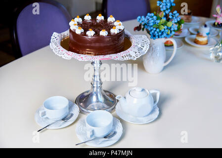 Le Moelleux au chocolat sur le stand se trouve sur une table avec des fleurs, divers desserts, tasses et une théière. Banque D'Images