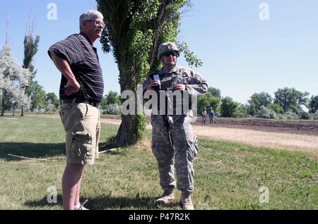 Mike Paris, directeur athlétique de la Sturgis Brown High School, et le Lt. Seth Allen de la 260th Engineer support Company de la Garde nationale de l'armée du Montana, inspectent le classement du nouveau terrain de football du lycée près de Sturgis, Dakota du Sud, le 17 juin 2016. Le projet fait partie de l’exercice d’entraînement Golden Coyote. Les nouveaux terrains fourniront un espace d’entraînement local à l’équipe de soccer de l’école secondaire, ce qui réduira les déplacements en ville et appuiera les programmes sportifs communautaires tout en démontrant la coordination de l’ingénierie et de la construction pendant les exercices d’entraînement annuels. Banque D'Images