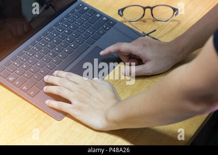 Les mains d'affaires travaillant sur ordinateur portable moderne sur l'espace de travail avec bureau en bois, Effet Lumière, focus de sélection. Banque D'Images