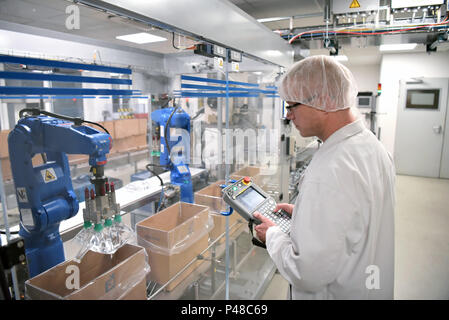 Travailleur de la courroie du convoyeur exploite un robot qui transporte les sacs d'insuline - usine moderne pour la production de médicaments dans le secteur des soins de santé Banque D'Images