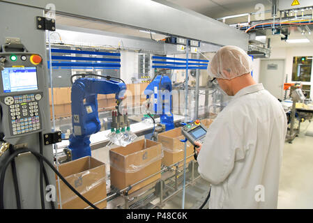 Travailleur de la courroie du convoyeur exploite un robot qui transporte les sacs d'insuline - usine moderne pour la production de médicaments dans le secteur des soins de santé Banque D'Images