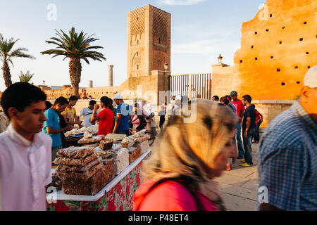 Rabat, Maroc : Les gens passent devant les restes de la Tour Hassan et la mosquée almohade. Destiné à être le plus grand dans le monde, ce dernier n'a pas unfinishe Banque D'Images