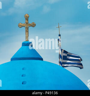 Dôme bleu et croix sur une église orthodoxe grecque avec le drapeau grec sur l'île égéenne de Santorin, Grèce Banque D'Images