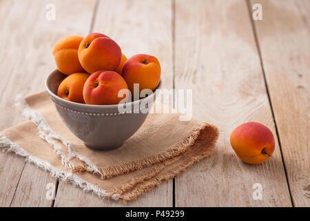 Joli bol d'abricots sur toile rustique avec fruits supplémentaires en arrière-plan Banque D'Images