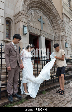 Jeune couple marié juste poser pour des photos de mariage en face de l'église catholique Saint Michel, Quingadao, Heilongjiang Province, C Banque D'Images