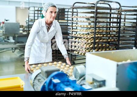 Employé de l'usine de confiserie holding tray with pâte non cuite Banque D'Images