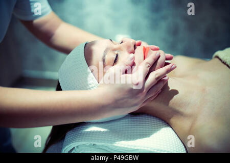 Massage du visage par un traitement professionnel à salon de beauté Banque D'Images