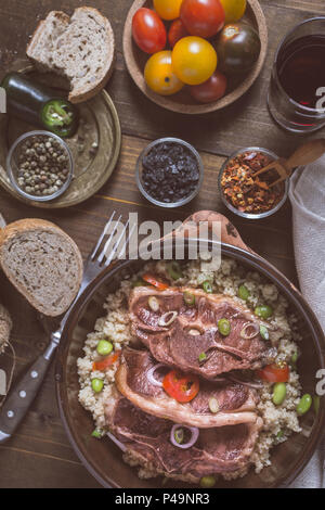 Côtelettes d'agneau rôtie avec le soja et le couscous dans un plat d'argile rustique Banque D'Images