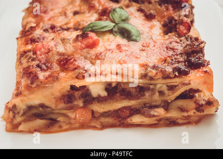 Des Lasagnes à la viande hachée, la sauce tomate et basilic frais on White Plate Banque D'Images