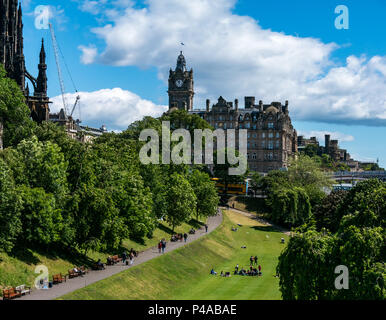 Edinburgh, Ecosse, Royaume-Uni, 21 juin 2018. Soleil dans le centre-ville, le premier jour de l'été avec les gens de vous détendre dans les jardins de Princes Street à l'heure du déjeuner. La tour de l'horloge de l'hôtel Balmoral est un monument du centre-ville avec le Scott Monument victorien gothique sur Princes Street Banque D'Images