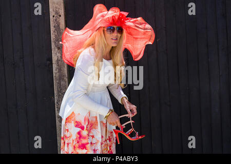 Ascot, Berkshire, Royaume-Uni. 21 juin 2018. Les Racegoers arrivent à Ascot dans leurs chapeaux et dans leur finery pour la fête des femmes à Royal Ascot pendant qu'ils se rendent à l'événement. Fashion on Ladies Day Royal Ascot - femme portant un grand chapeau et des lunettes de soleil, tenant la chaussure comme elle change ses chaussures pour la journée. Crédit : Carolyn Jenkins/Alay Live News Banque D'Images