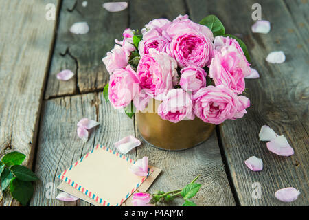 Plateau rose tendre bouquet de roses vintage en pot et vierge de carte de souhaits sur la vieille table en bois rustique. Floral background. Maquette de carte postale. L'été, sprin Banque D'Images