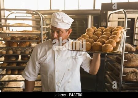 Male baker holding a tray d'aliments sucrés cuits au four Banque D'Images