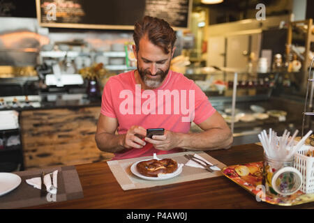 L'homme à l'aide de téléphone mobile dans une boulangerie Banque D'Images