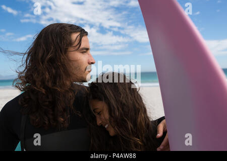 Surfer couple standing with surfboard dans la plage Banque D'Images