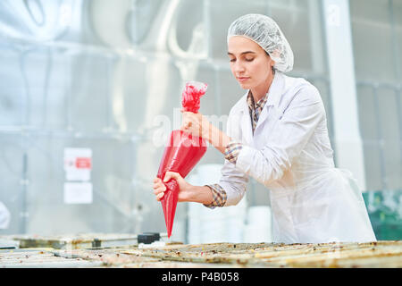 Employé de l'usine de confiserie squeezing poche à pâtisserie Banque D'Images