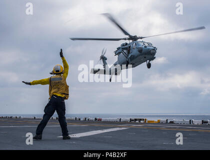 160625-N-JW440-016 OCÉAN ATLANTIQUE (25 juin 2016) l'Aviation maître de Manœuvre (manutention) 3e classe Demarcus Robinson dirige un MH-60S Sea Hawk à la terre à bord du navire d'assaut amphibie USS Wasp LHD (1). Le Wasp est déployé avec le groupe amphibie Wasp pour appuyer les opérations de sécurité maritime et les efforts de coopération en matière de sécurité dans le théâtre américain dans la flotte de 5ème et 6ème zones d'opération. (U.S. Photo par marine Spécialiste de la communication de masse 3 Classe Rawad Madanat/libérés) Banque D'Images