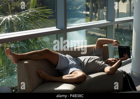 Livre élève lit tout en jetant sur le canapé à Sun à l'Université de Miami, Floride, Student Union. Banque D'Images