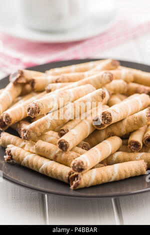 Rouleaux de gaufrettes au chocolat sucré sur la plaque. Banque D'Images